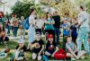 A diverse group of families and children enjoying an outdoor event on a sunny day in a park setting.